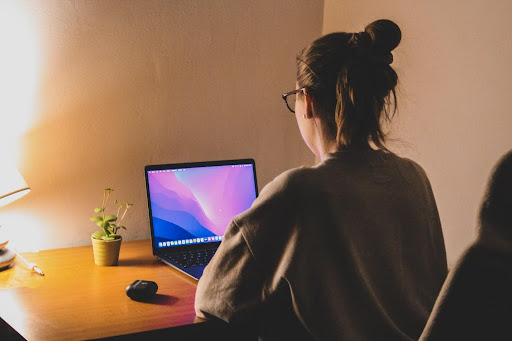 A Personal Social Media Assistant sits at a desk, focused on a laptop screen. They are engaged in various tasks, managing social media platforms, and optimizing content to enhance online presence and engagement.